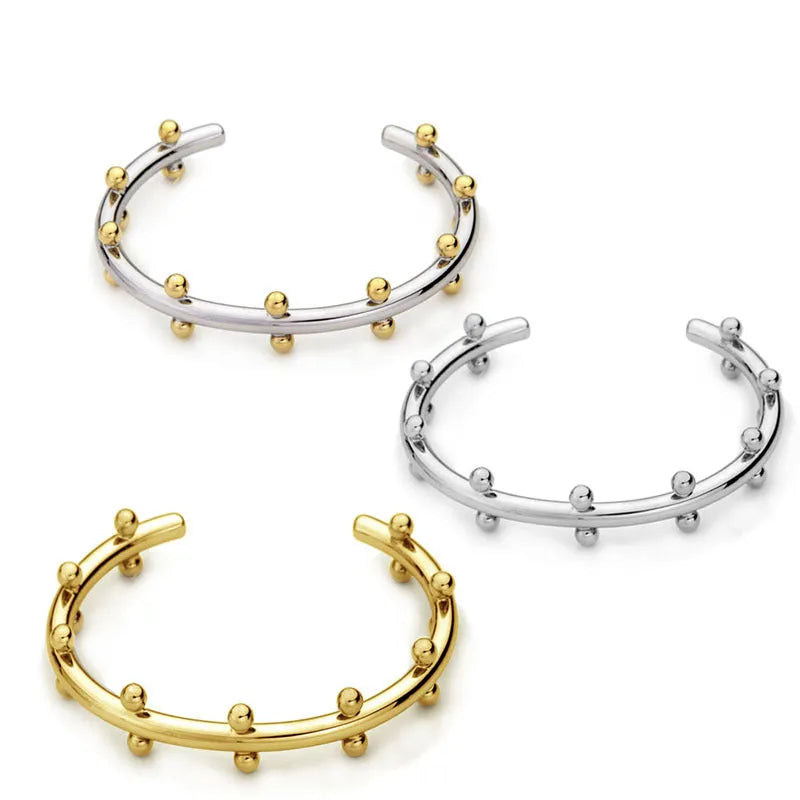 C-shaped stainless steel alloy bracelet with textured rivet-shaped beads on a wrist.