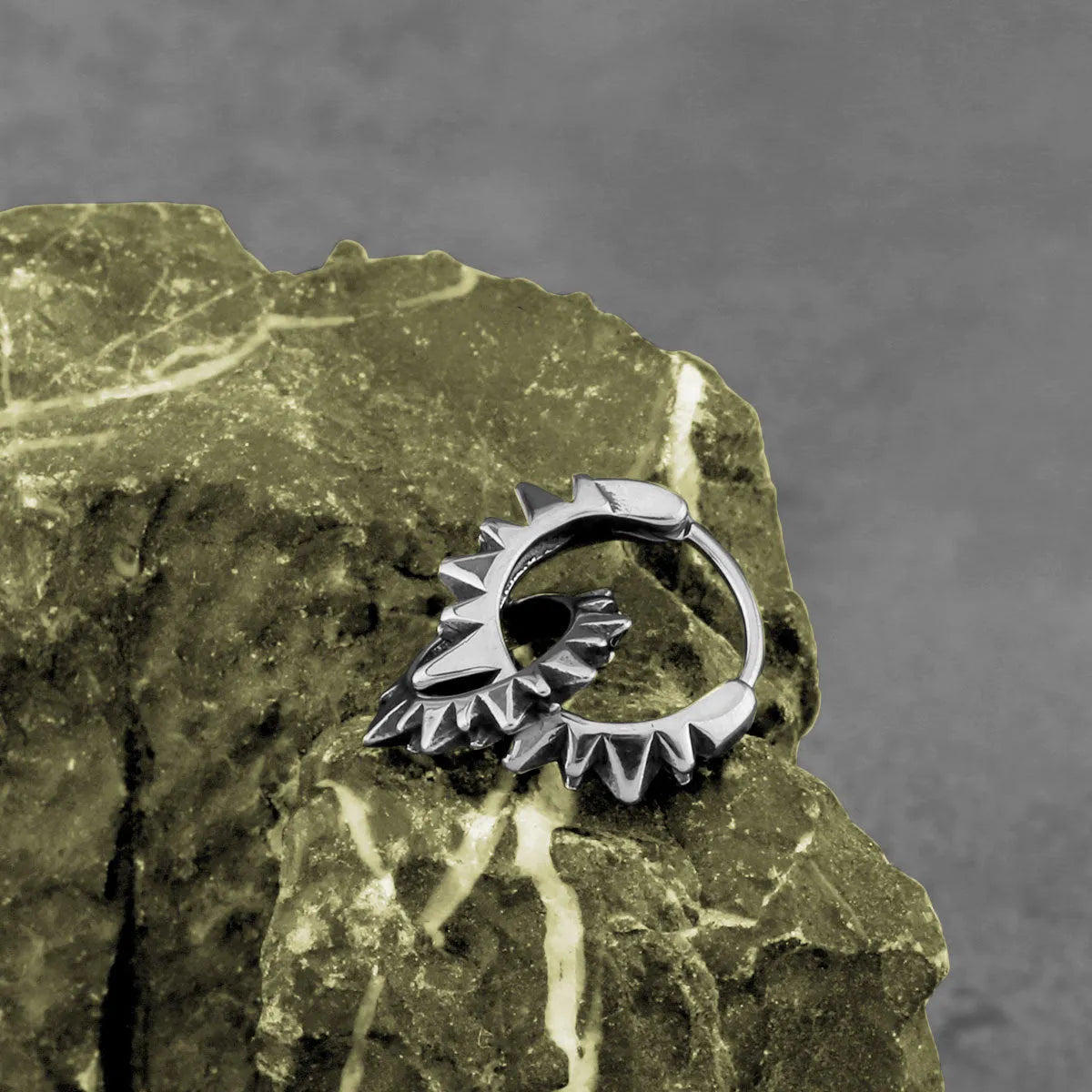 A pair of simple, polished stainless steel round ring hoop earrings on a steel colour background.