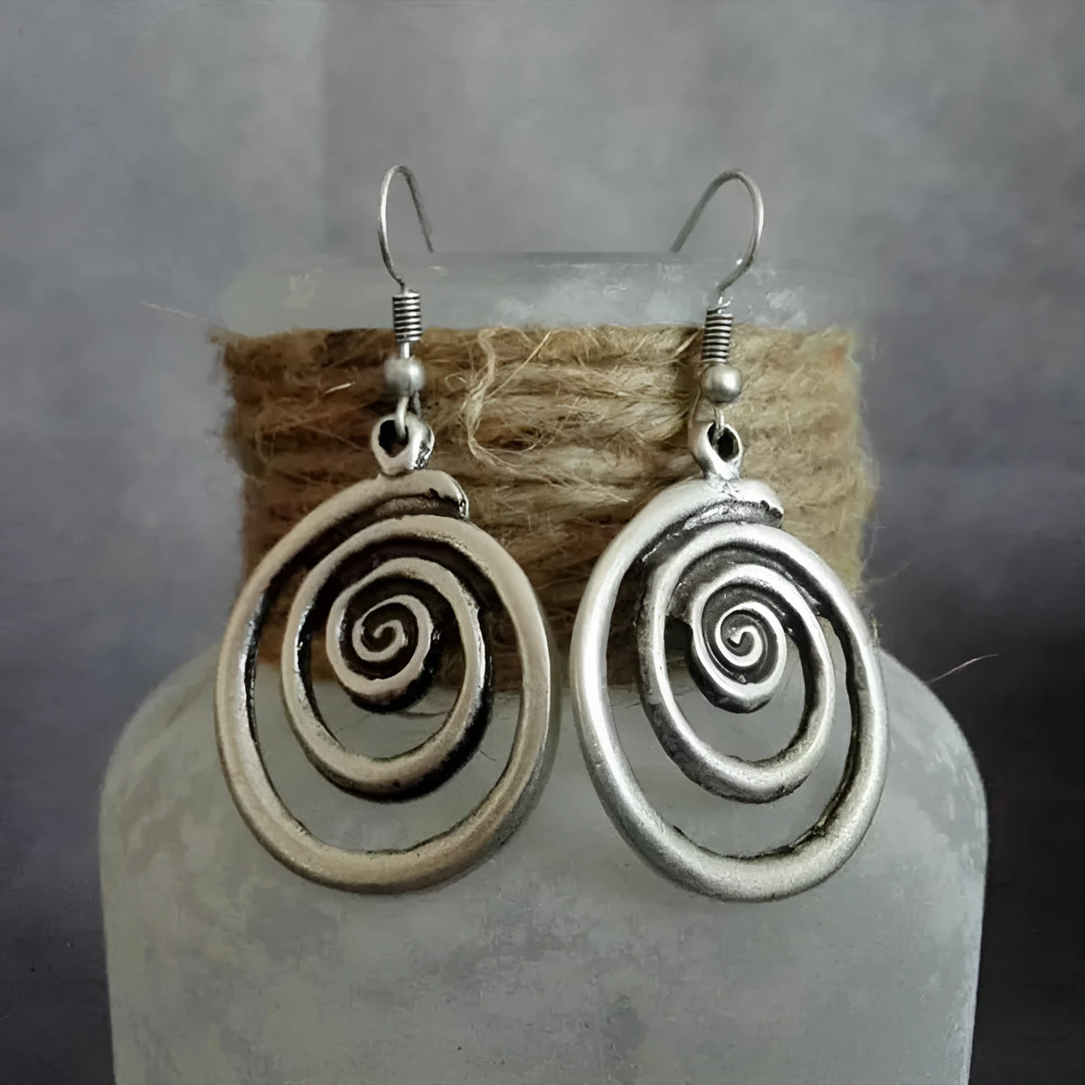 A pair of silver-coloured geometric spiral earrings with a distressed metal finish
