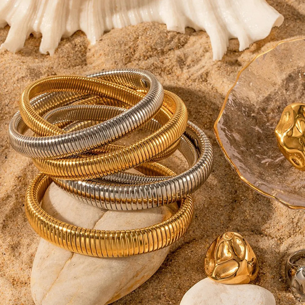 Gold titanium steel women's bracelet with vertical stripes and elastic ring design on a wrist.