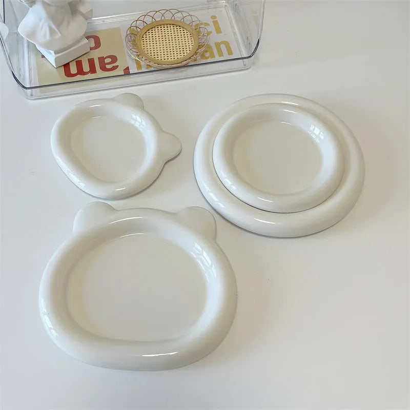 White porcelain plate with chubby toot design, showing bear or round doodle pattern, on a table.
