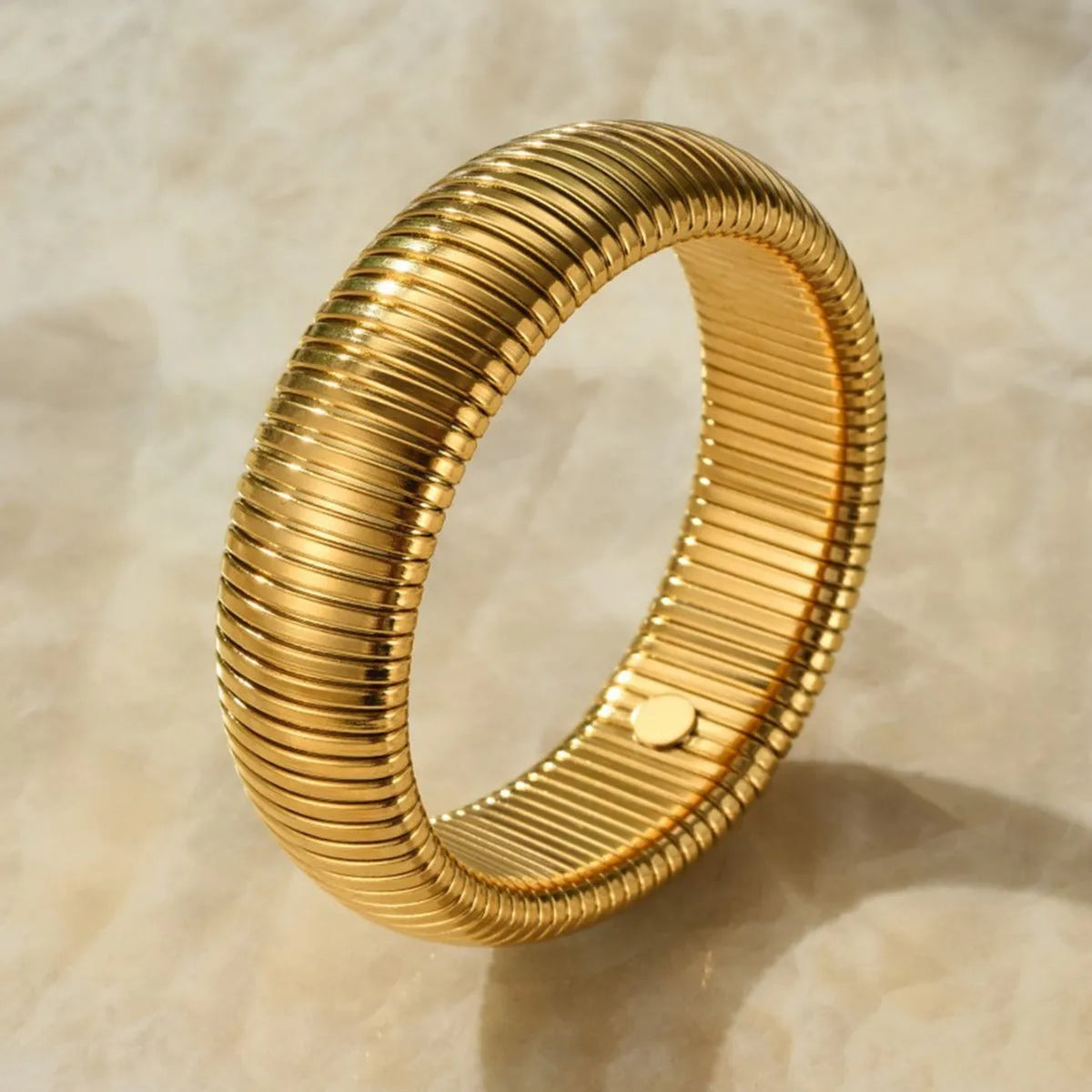 Gold titanium steel women's bracelet with vertical stripes and elastic ring design on a wrist.