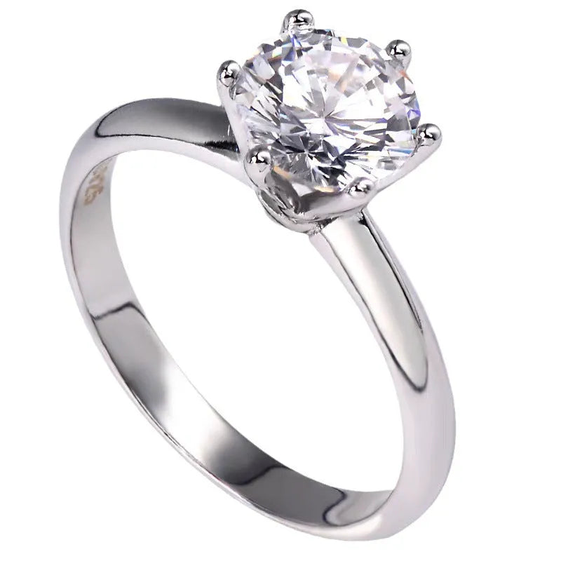 Close-up view of a white gold plated six-claw zircon ring on a finger, showing geometric design.