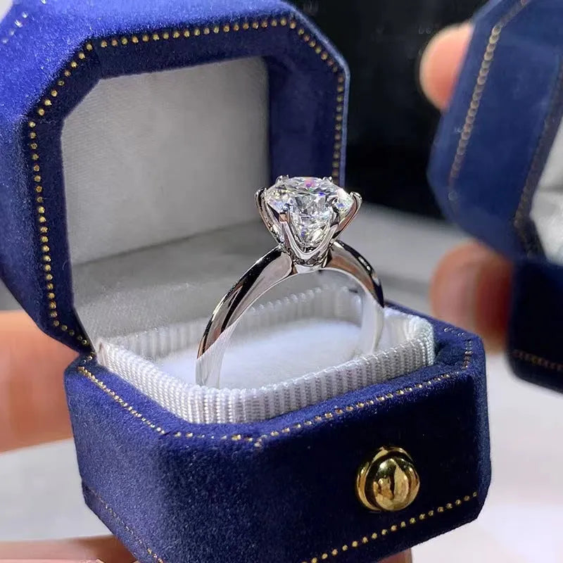 Close-up view of a white gold plated six-claw zircon ring on a finger, showing geometric design.
