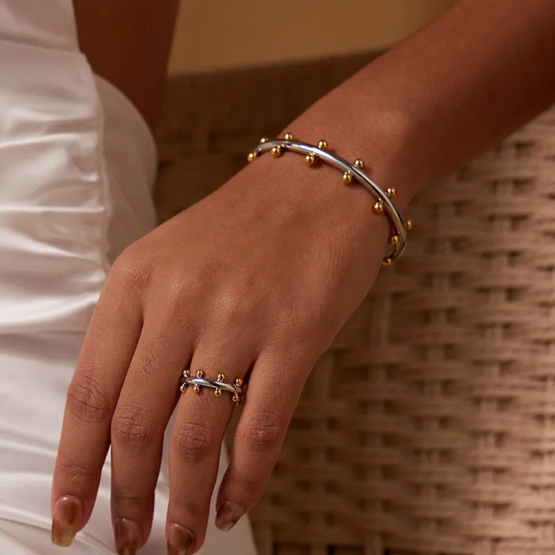 C-shaped stainless steel alloy bracelet with textured rivet-shaped beads on a wrist.