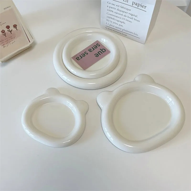 White porcelain plate with chubby toot design, showing bear or round doodle pattern, on a table.