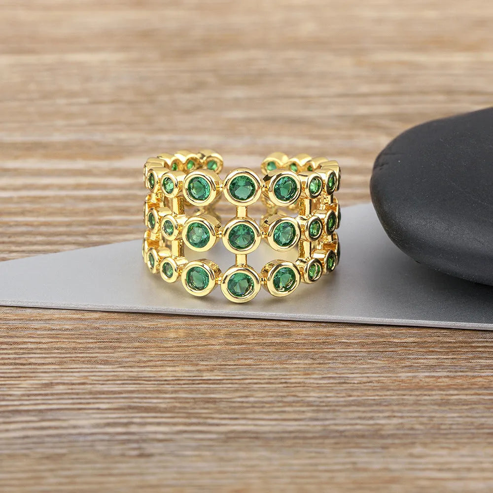 Copper ring with 18K gold plating showing three-layer design and green zircon stones