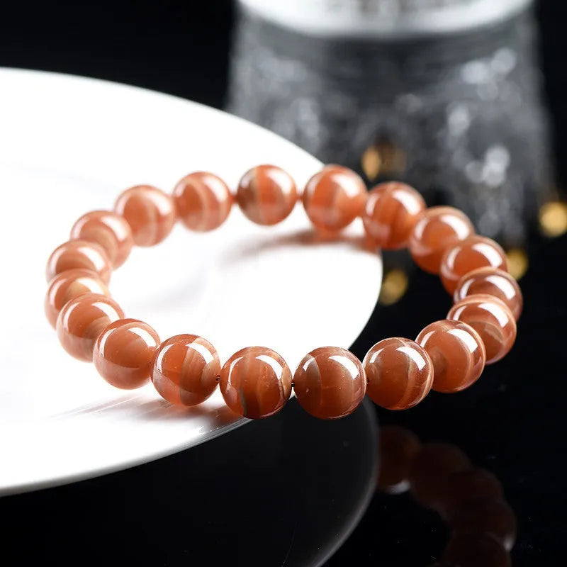 Natural Old Mine Rhodochrosite round bead bracelet with Ruyi design elements on a wrist.