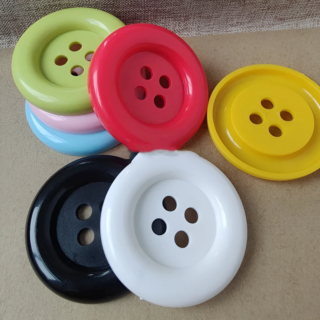Oversized plastic nylon buttons in multiple colours with round edges and four stitching holes