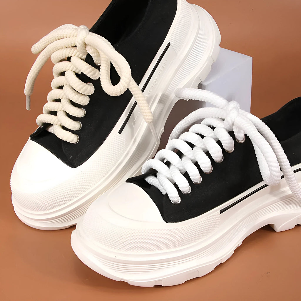Round white woven shoelace with 10mm diameter next to a beige and black lace on a grey background.