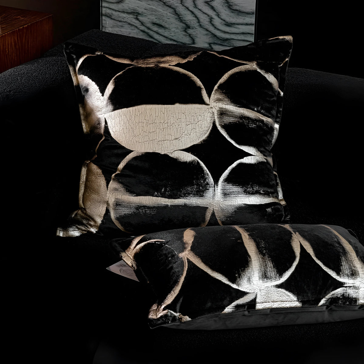 Black and gold abstract pattern square cushion with removable feather velvet cover on a sofa.