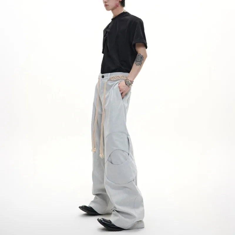 Men's dark blue loose straight-leg jeans with 3D cutting, heavy belt stitching, and pocket tassel details.