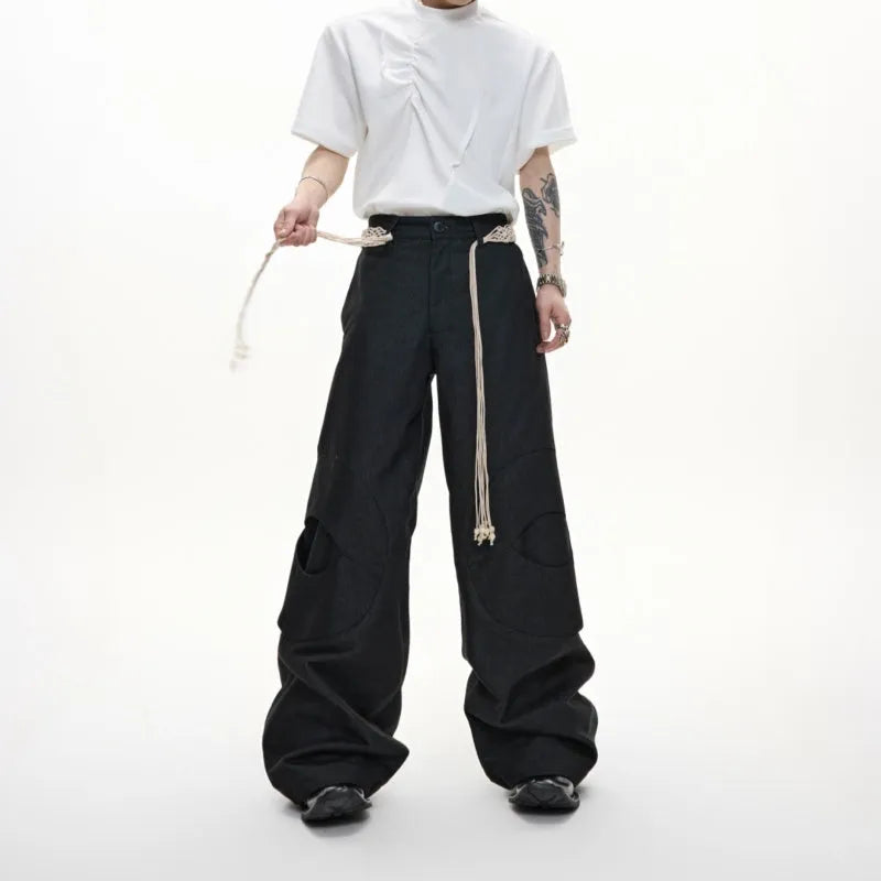 Men's dark blue loose straight-leg jeans with 3D cutting, heavy belt stitching, and pocket tassel details.