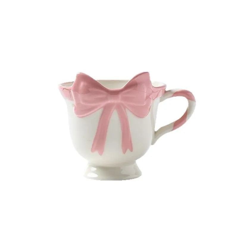 Cute white ceramic mug with a black heart bow design and printed handle ornament.