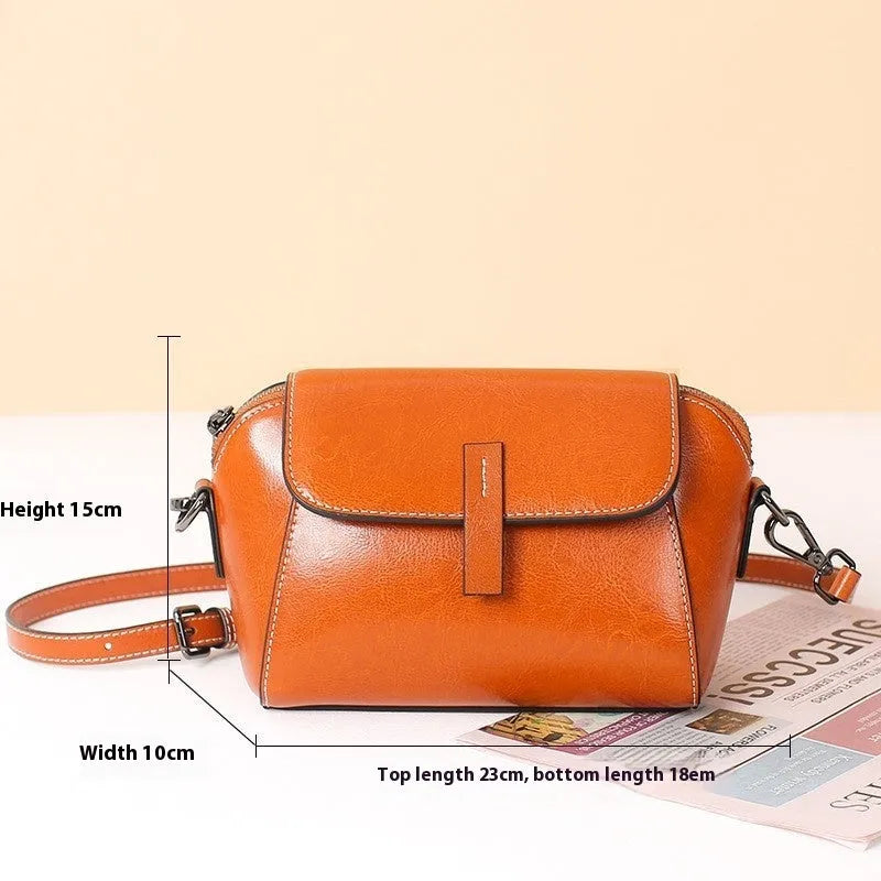 Women's brown shell-shaped messenger bag made of oil wax leather with a cross-body strap.