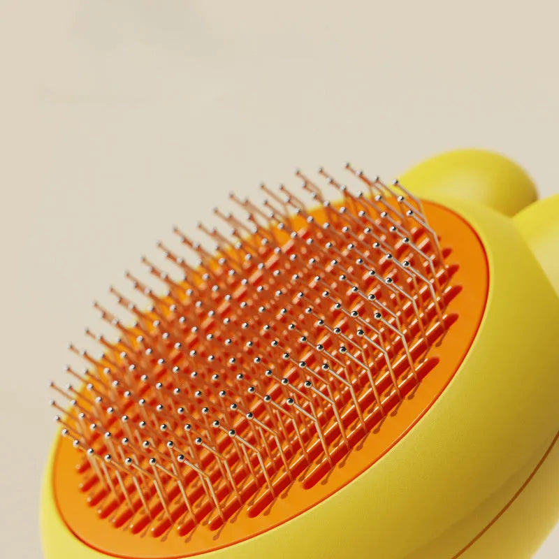 Self-cleaning pet grooming brush with release button showing stainless steel teeth and ergonomic handle
