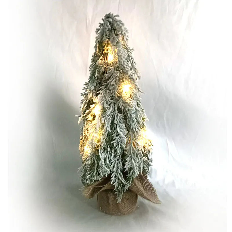 Small white artificial Christmas tree with built-in lights and snow sprayer decoration on desktop