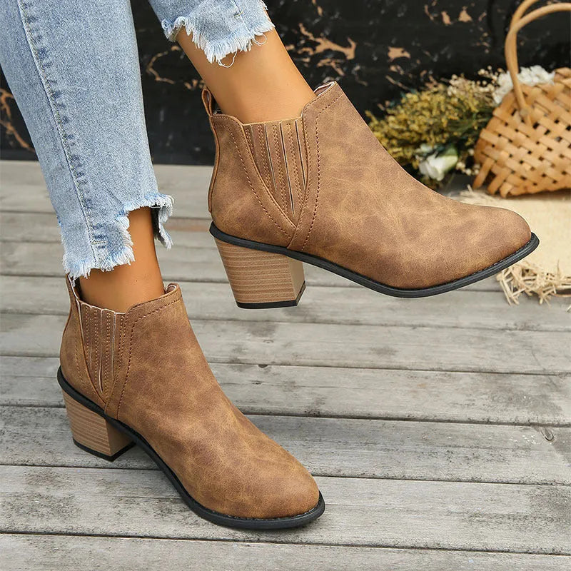Women's black ankle boots with pointed toes and thick square heels on a solid background