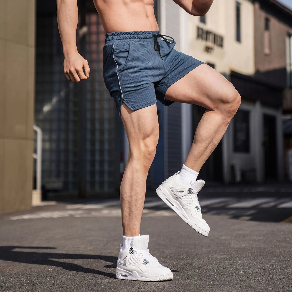 Man wearing straight-leg polyester sports shorts in grey, sizes M to 3XL available.