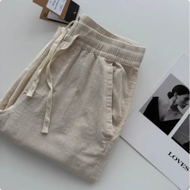 Men's loose straight casual pants with drawstring waist in beige, shown laid flat.