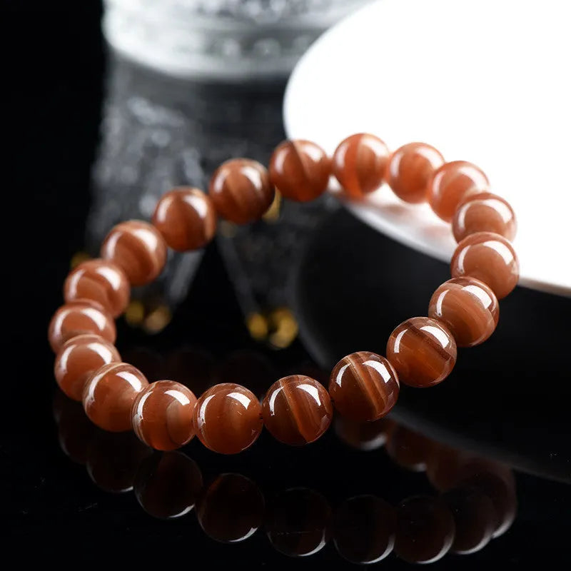 Natural Old Mine Rhodochrosite round bead bracelet with Ruyi design elements on a wrist.