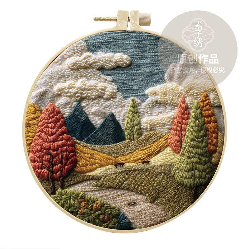 Embroidery DIY kit with cotton landscape fabric, bamboo frame, needles, and thread on wooden table