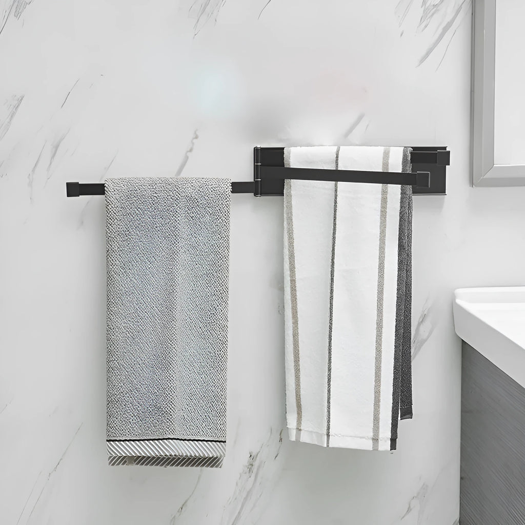 Black folding towel rack mounted on bathroom wall with towel hanging