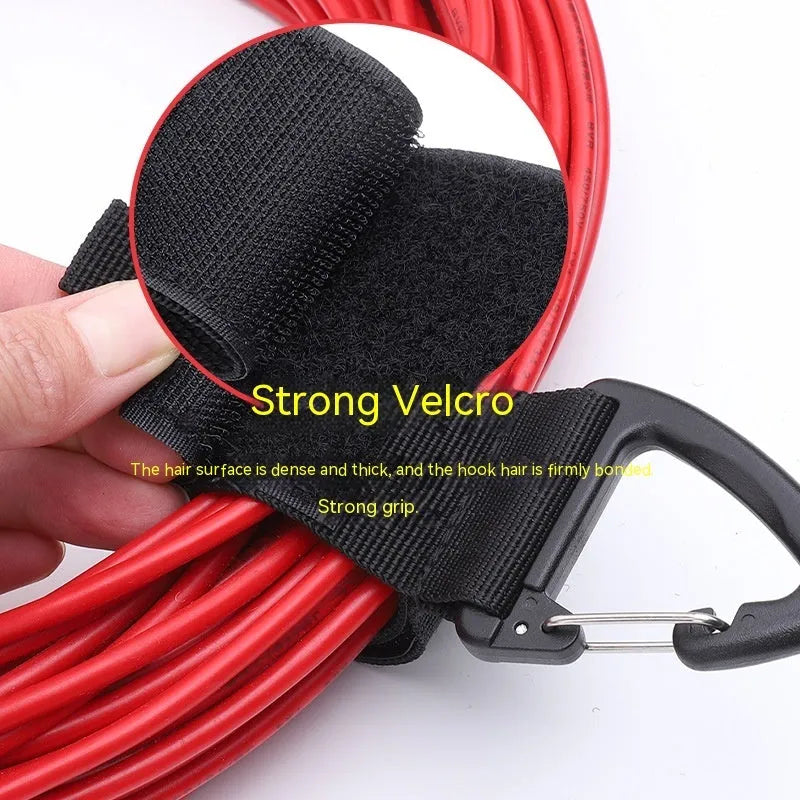Black heavy gravity climbing storage strap with carabiner hook shown extended vertically