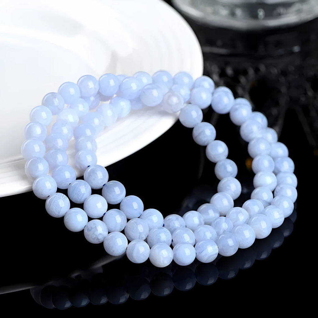 Blue agate bead bracelet with striped pattern and ruyi design on a white background.