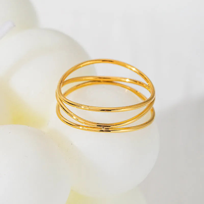 Geometric gold titanium steel coil ring showing three-layer design on a model's finger.