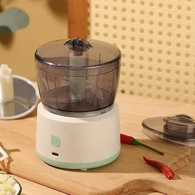 Mini electric meat grinder with transparent bowl and stainless steel blades on anti-slip pad