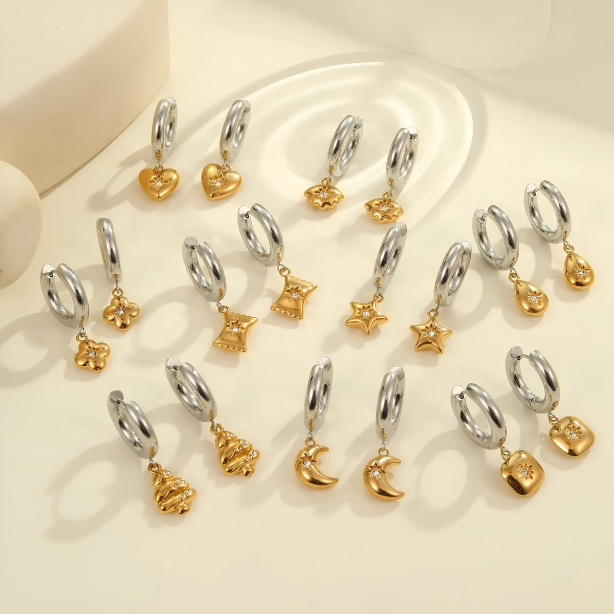 A pair of gold-coloured stainless steel earrings featuring a Christmas tree design and a heart shape with star details.