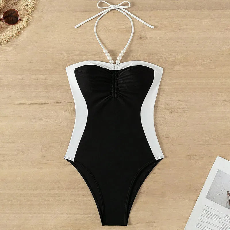 Black and white women's one-piece swimsuit with pearl-decorated spaghetti straps for a slimming fit.