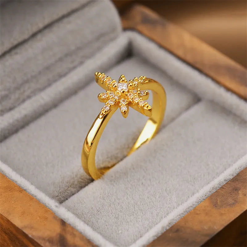 Gold geometric open fashion ring made from electroplated copper on a plain background.