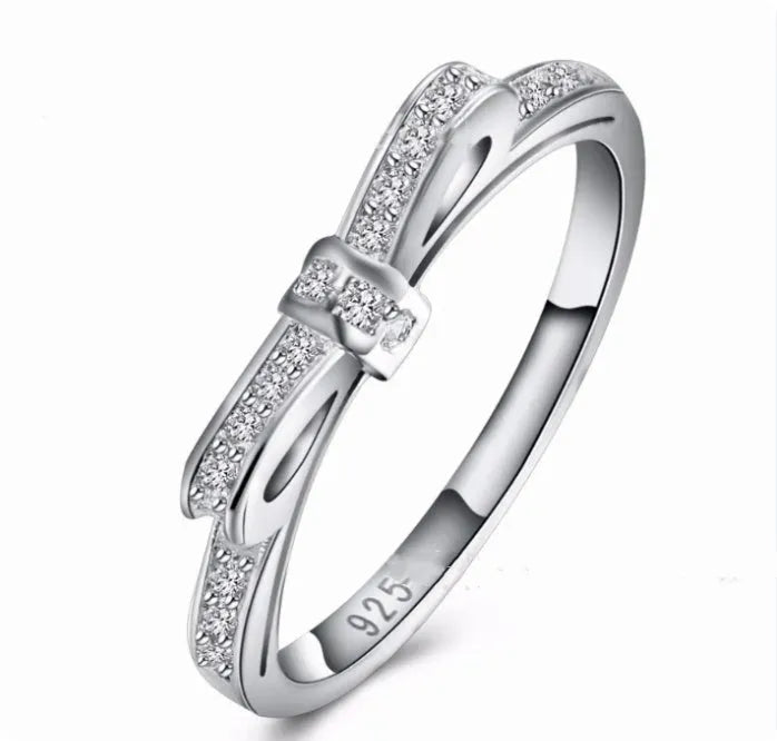 Silver couple's ring with a bow shape and sparkling zircon crystal rhinestones on a finger.