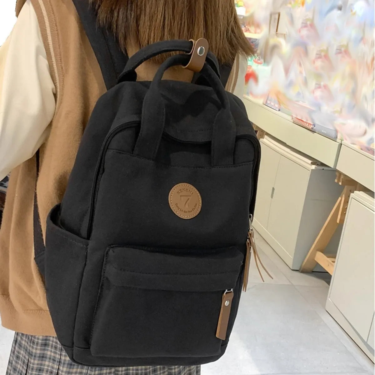 Solid black Oxford cloth leisure backpack with curved shoulder straps and retro styling details
