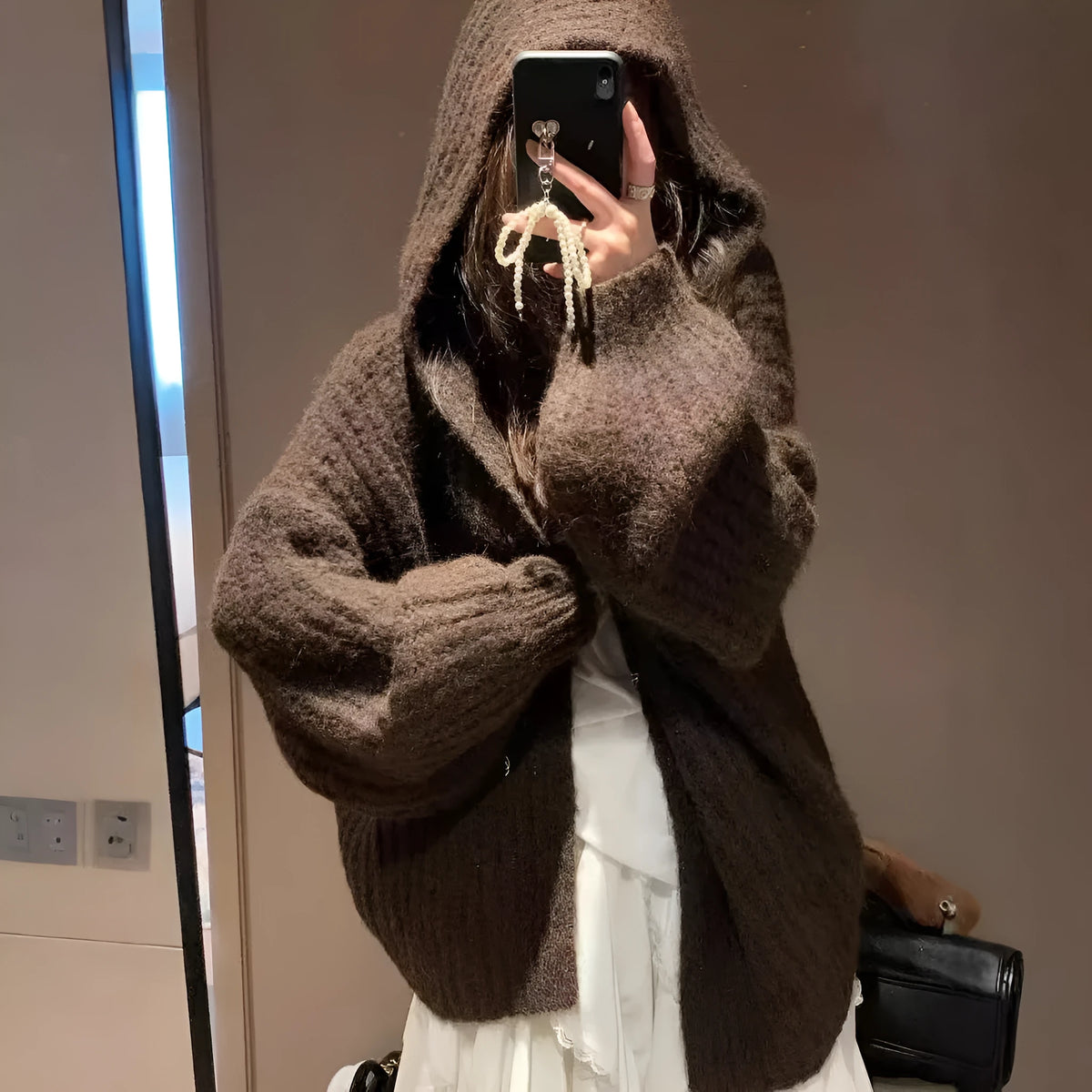 A woman wearing a thick, dark gray retro-style hooded cardigan with regular sleeves.