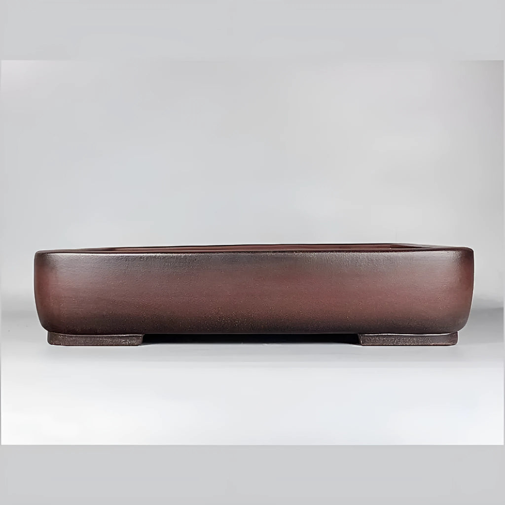 Handmade antique rectangular purple clay flower pot on a wooden surface.