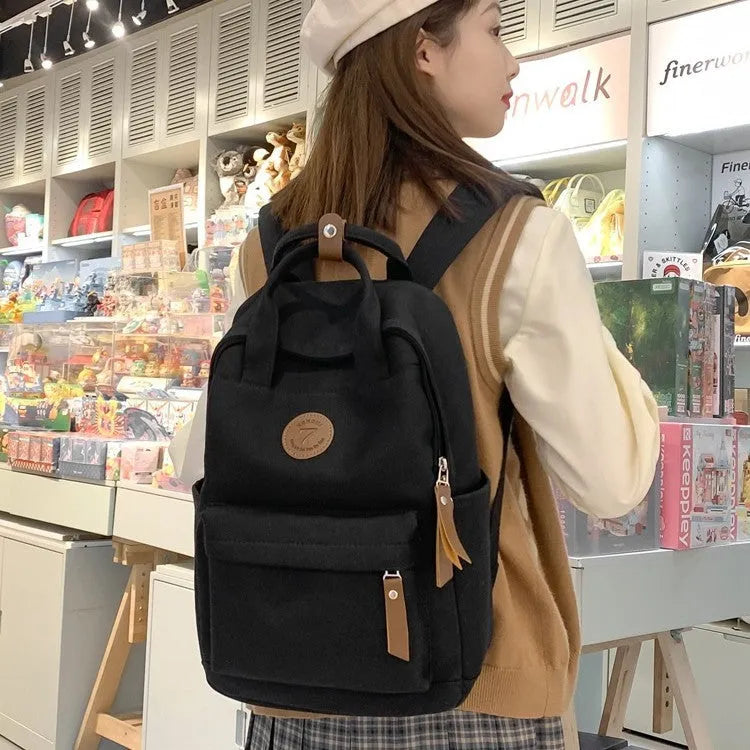 Solid black Oxford cloth leisure backpack with curved shoulder straps and retro styling details