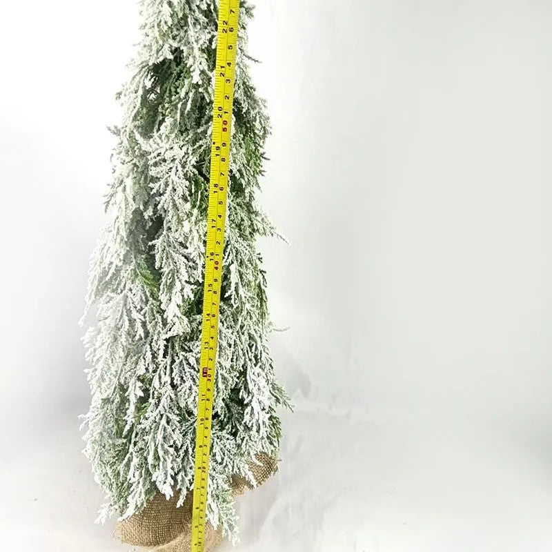 Small white artificial Christmas tree with built-in lights and snow sprayer decoration on desktop