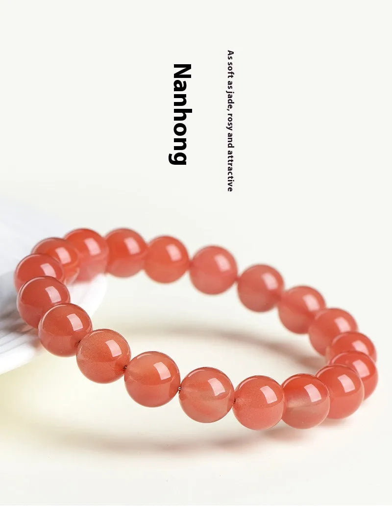 Loose polished cherry red agate beads in various sizes for bracelet making on a white surface.