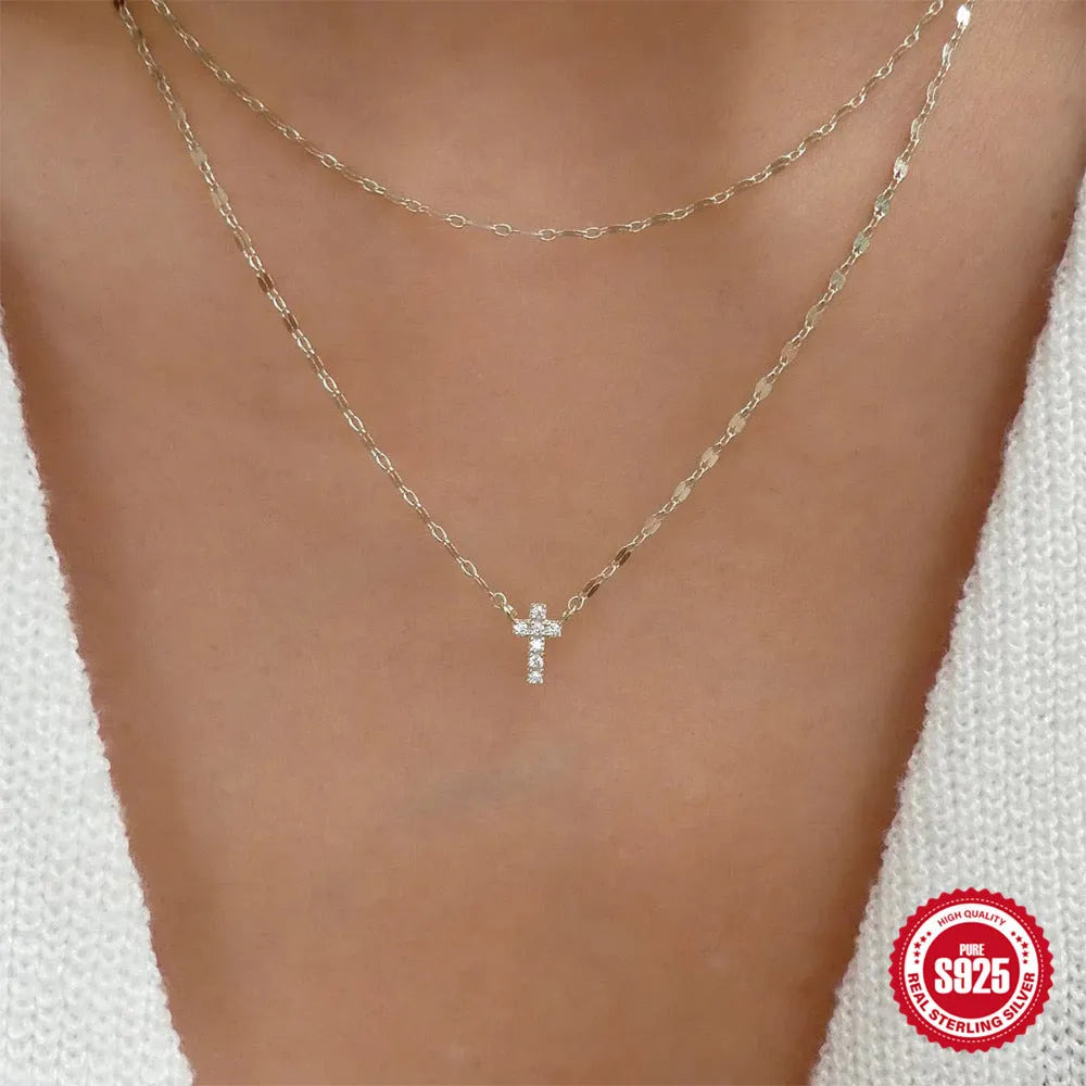 Close-up of a sterling silver double-layer geometric cross pendant on a clavicle chain.