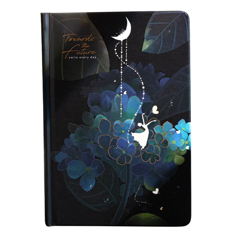A5 notebook with a luminous cover open to show pages with colour illustrations, in deep blue, gold, light blue, or purple.