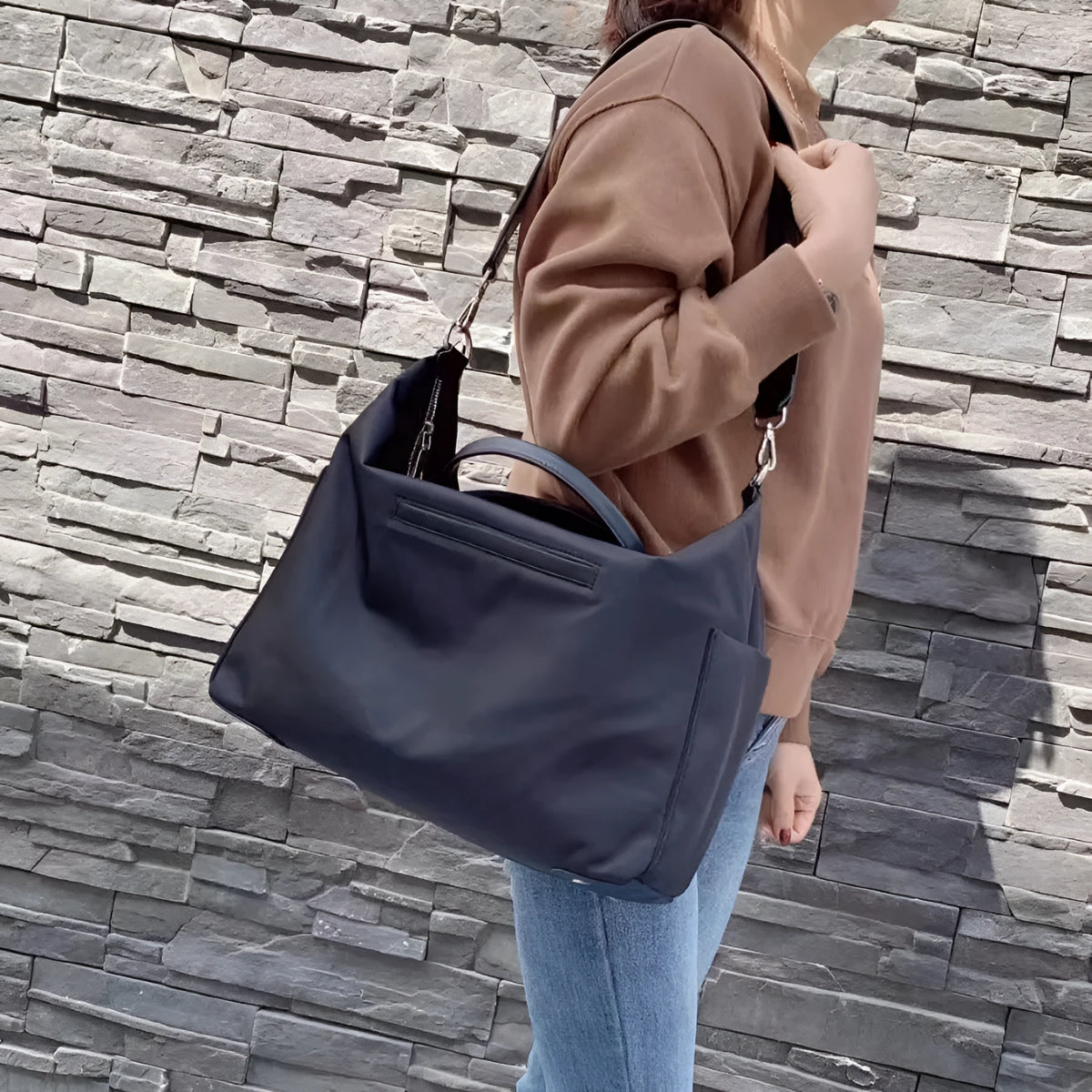 Black nylon waterproof shoulder bag with leather detailing, showing its large capacity.