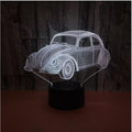 Modern black or crack finish 3D LED table lamp with touch controls and remote on a desk.