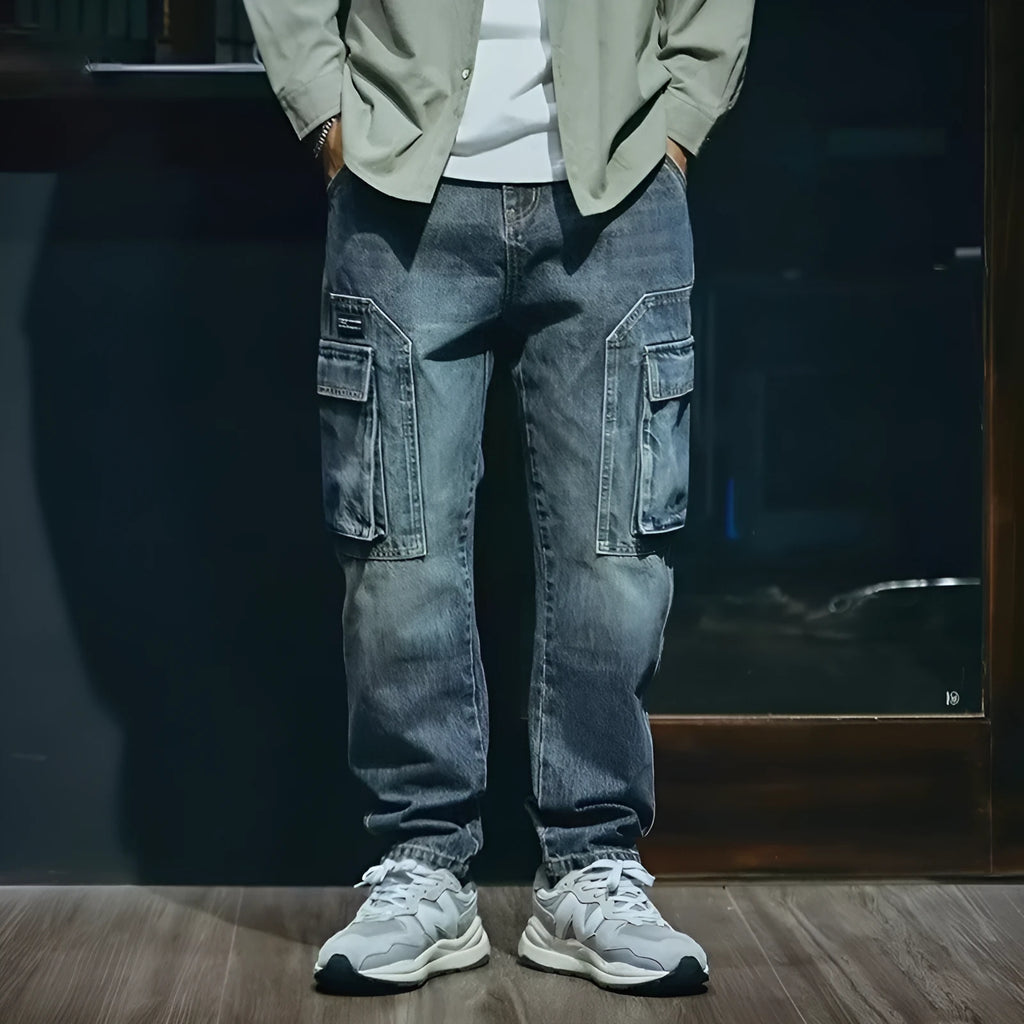 Man wearing blue loose straight-leg retro jeans with a zip fly, shown in a casual setting.