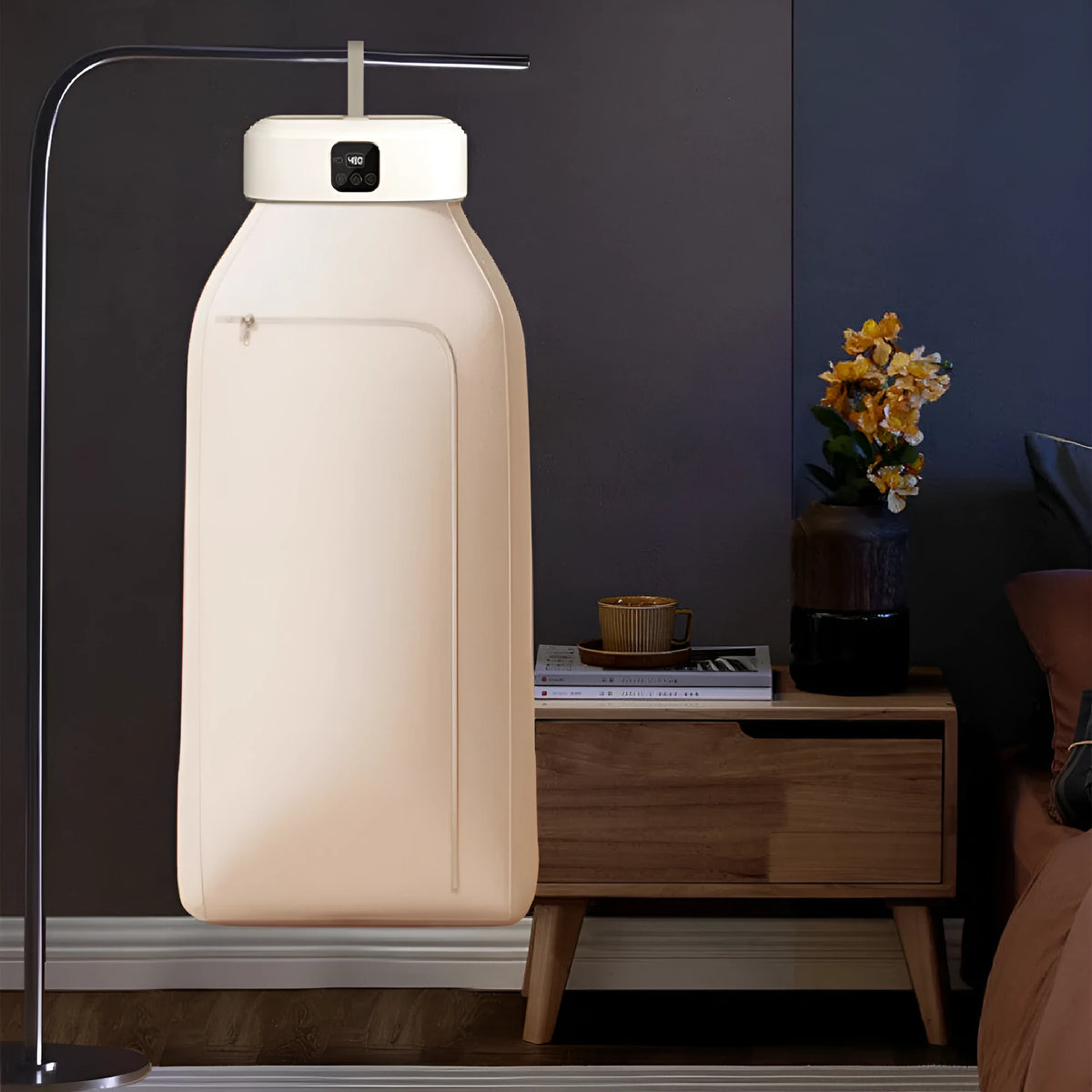 White cylindrical compact electric clothes dryer with remote control on a table.
