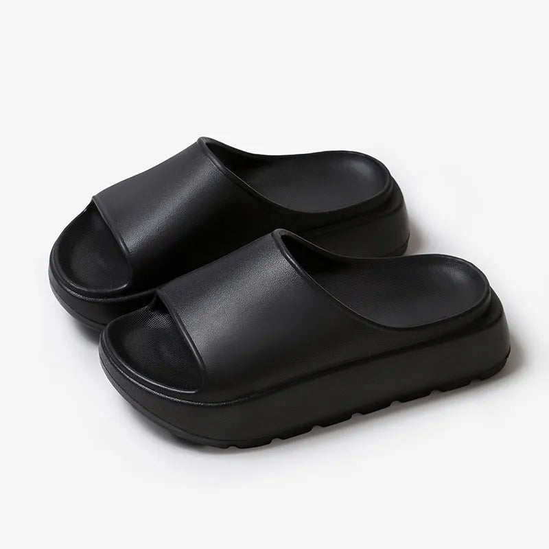 Women's thick-soled beige beach slippers with fish mouth design on a wooden deck.