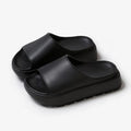 Women's thick-soled beige beach slippers with fish mouth design on a wooden deck.