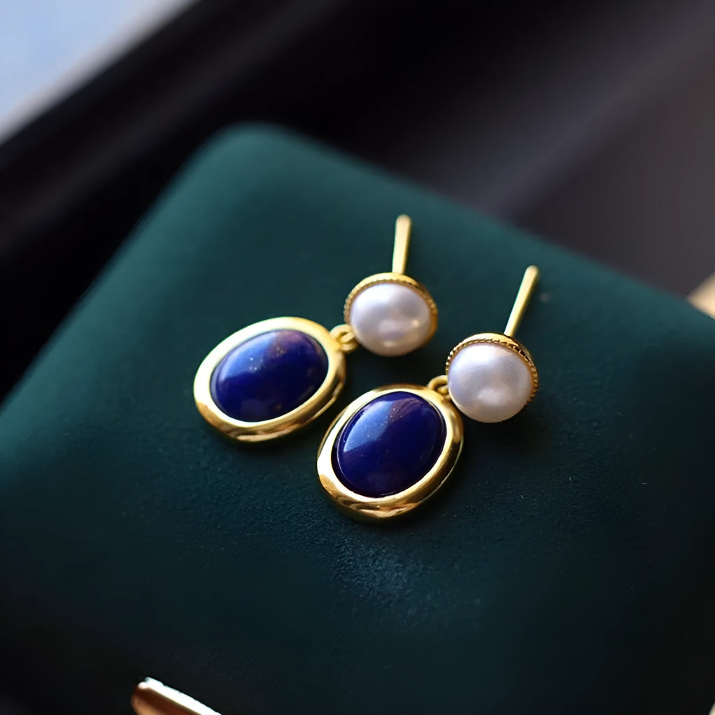 A pair of 925 sterling silver stud earrings with a deep blue lapis lazuli pearl and auspicious pattern details.
